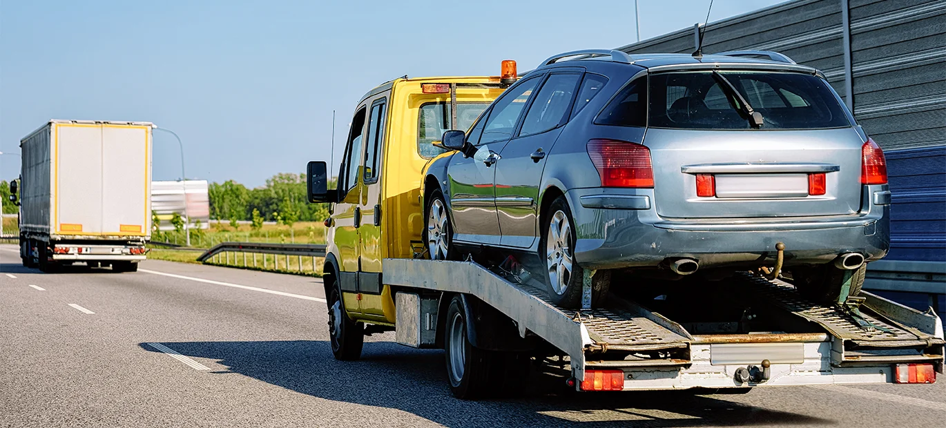 The car was towed on a flatbed recovery truck on a motorway.