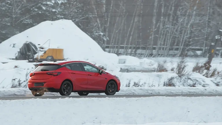 A car navigates a snow-covered road in winter.