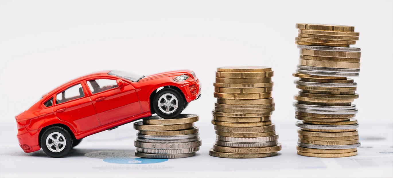 A car perched atop a stack of coins, symbolizing towing expenses.