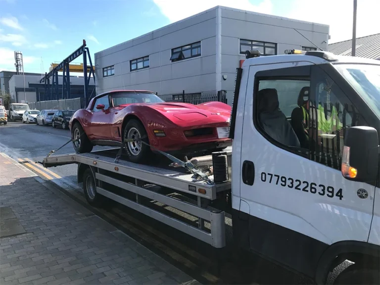 Specialist vehicle recovery in Ealing: Secure transport of a classic red Corvette on a flatbed recovery truck.